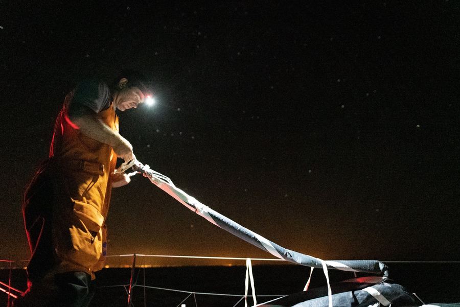 11th Hour Racing crew working on deck at night by head torch